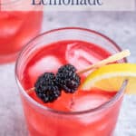 A glass of lemonade with blackberries and a lemon slice.
