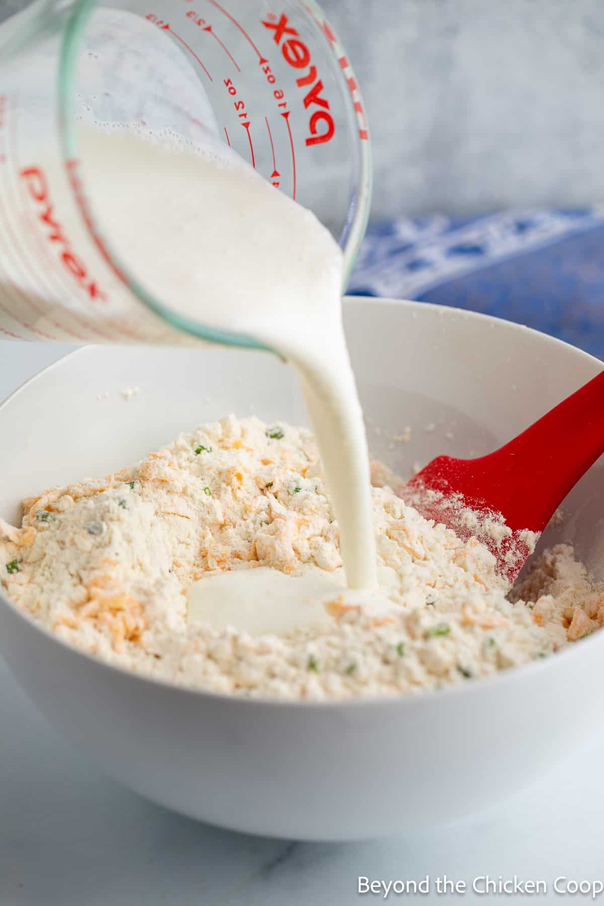 Pouring buttermilk into a bowl with flour. 