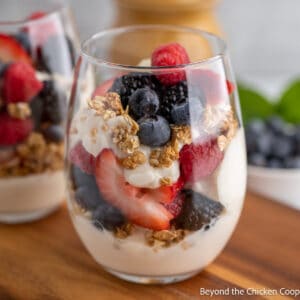 A glass filled with layers of yogurt, berries and granola.