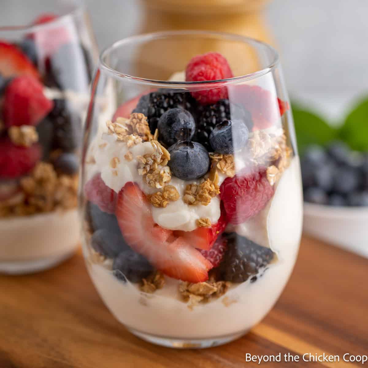A glass filled with layers of yogurt, berries and granola. 