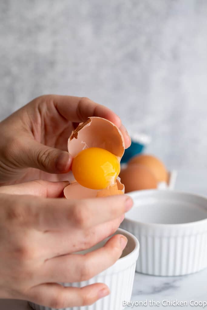 Dumping an egg yolk into a half of an eggshell. 