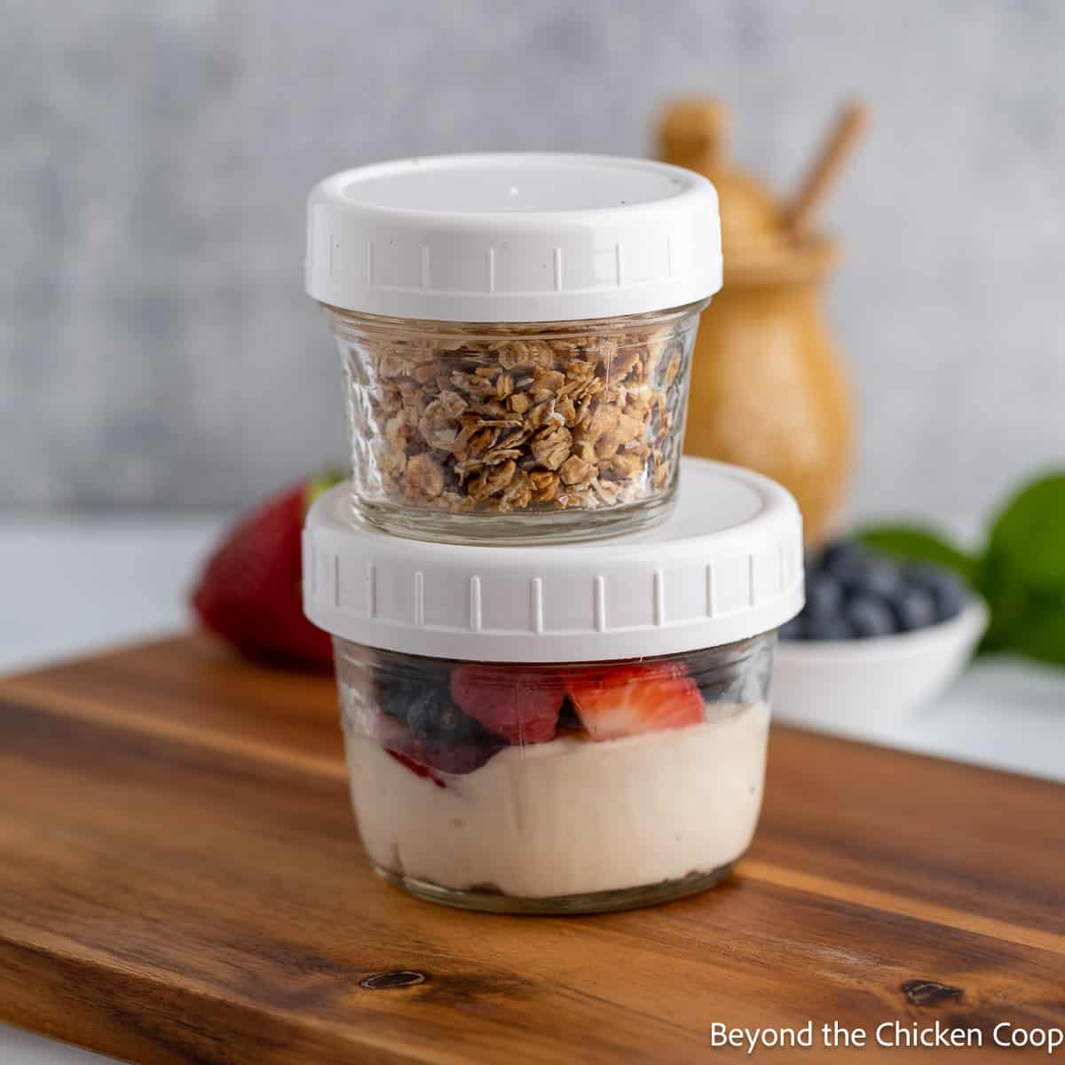 Two glass jars filled with yogurt, fruit and granola.