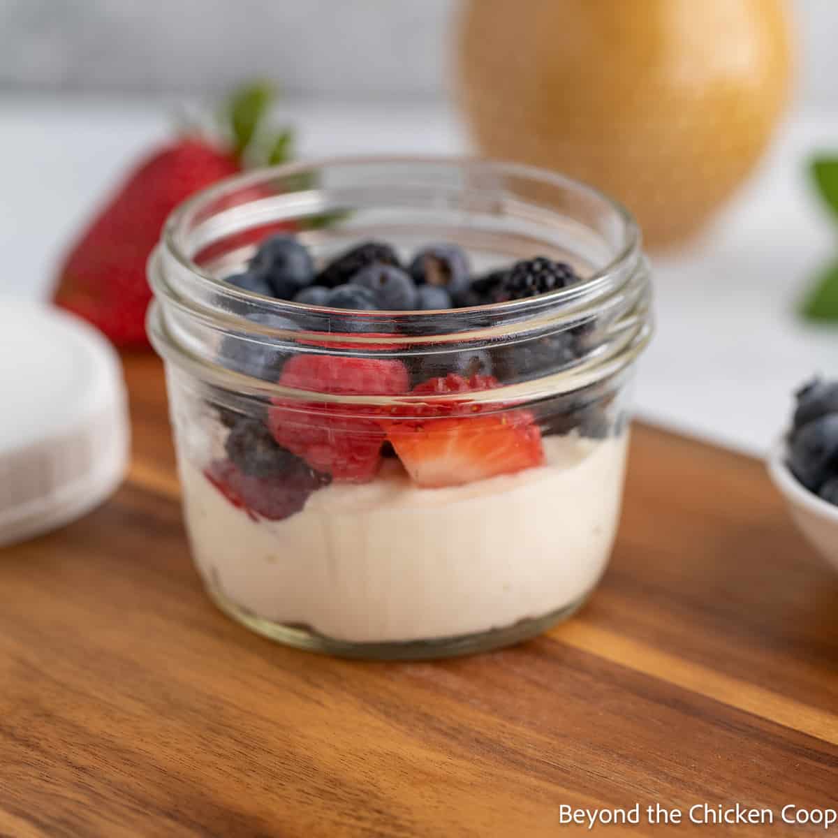 Glass jar filled with yogurt and berries.