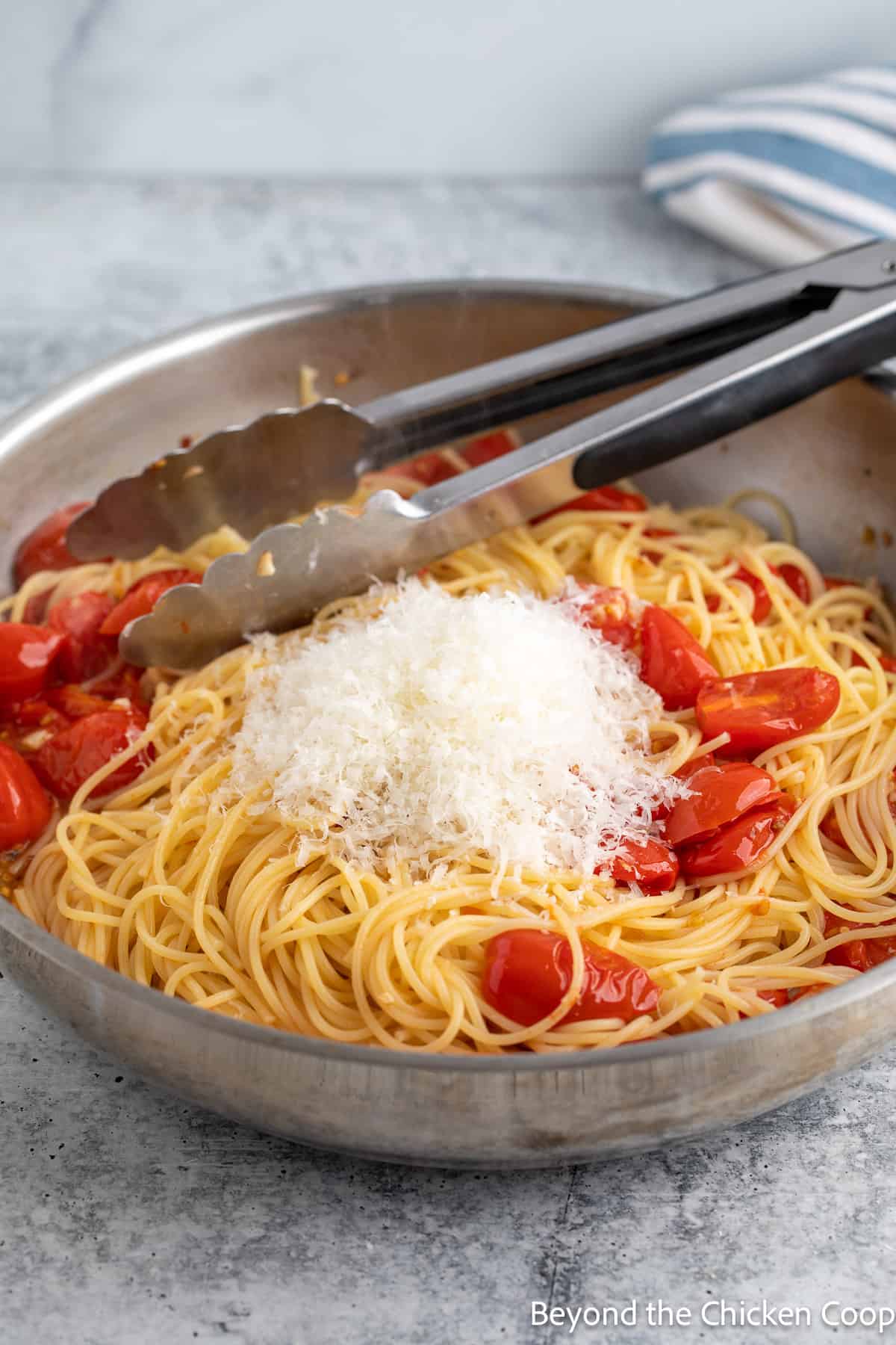 Shredded parmesan cheese added to a pan of pasta.