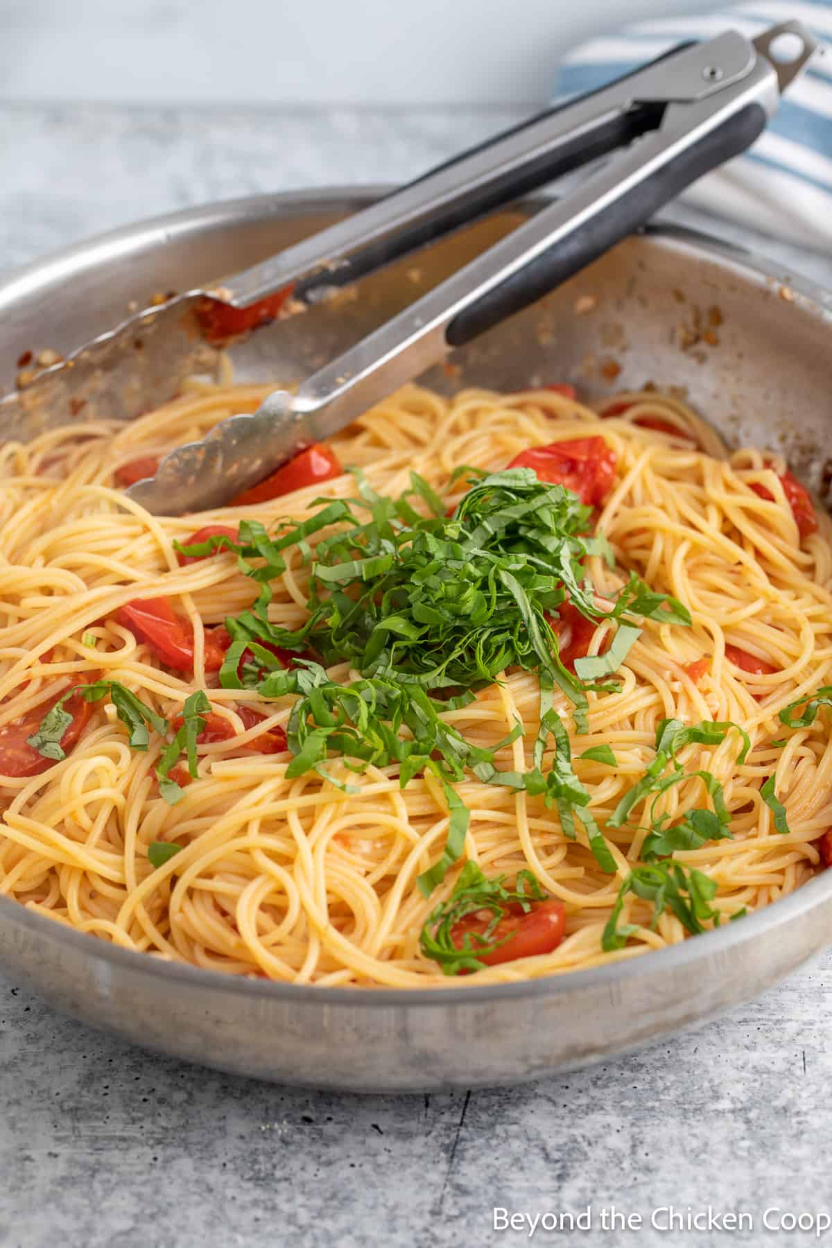 Sliced basil in a pan with pasta and tomatoes. 