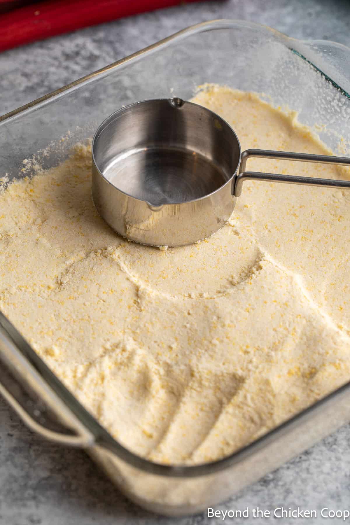 Patting down a crust with a measuring cup.