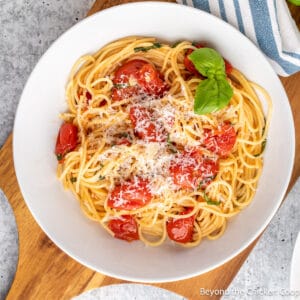 Pasta in a bowl with cherry tomatoes and basil.