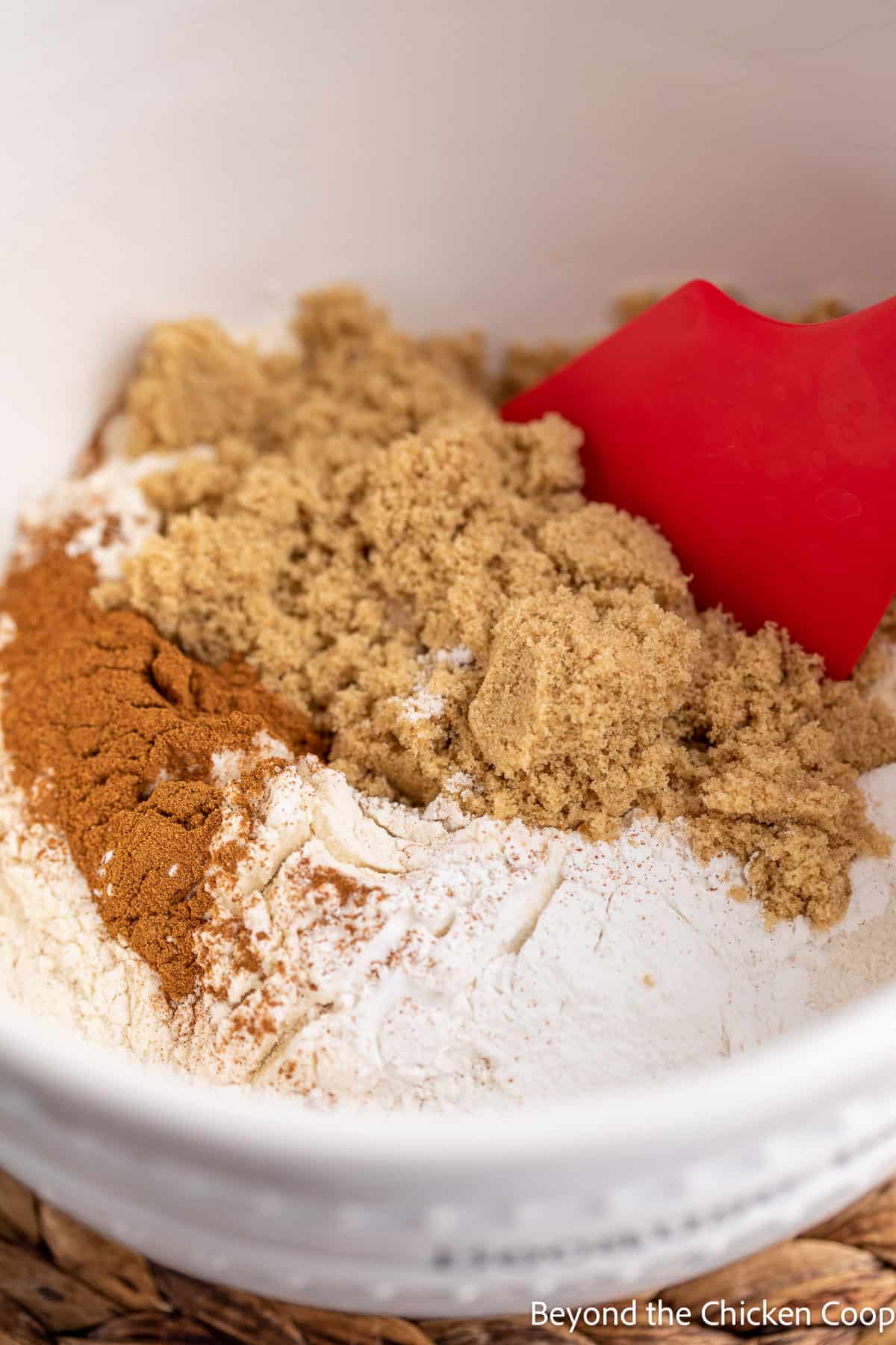 Mixing flour, brown sugar and cinnamon in a white bowl. 