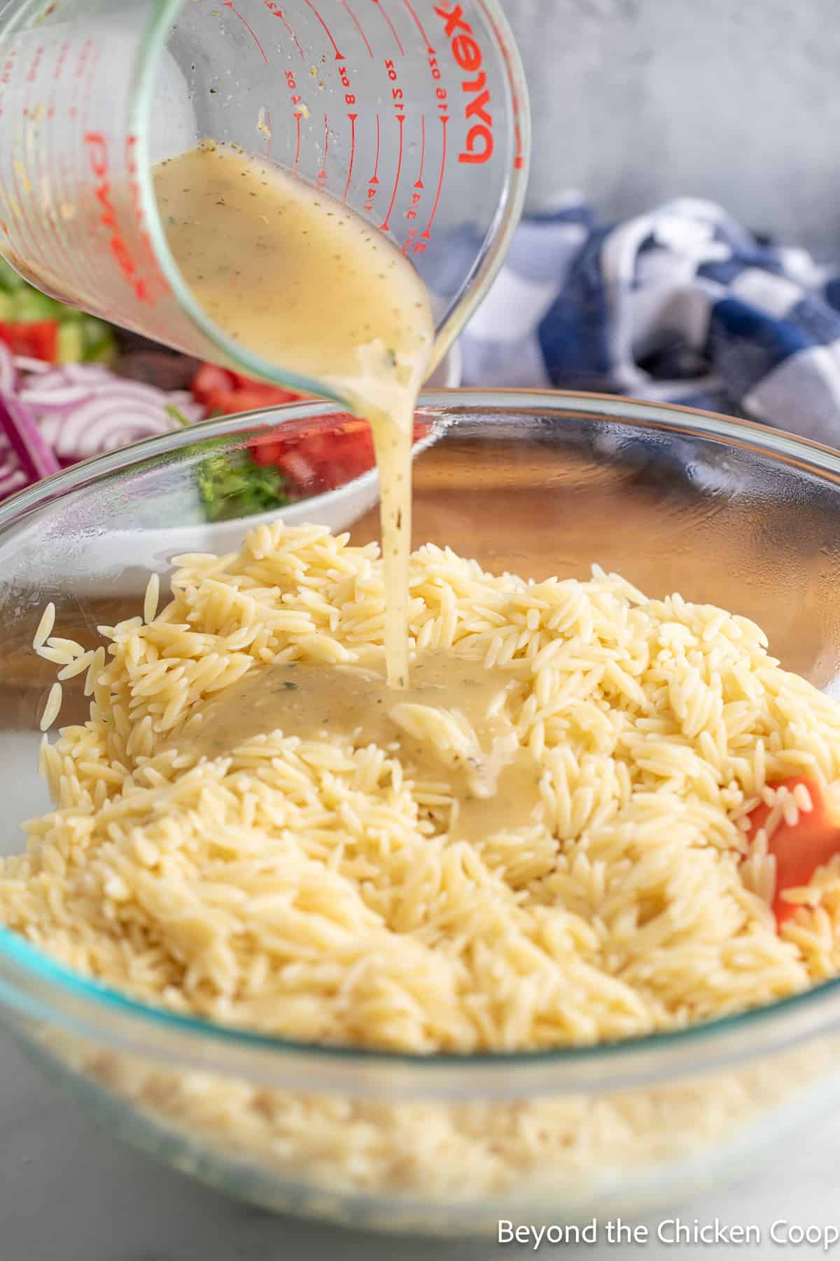 Pouring dressing over orzo pasta. 