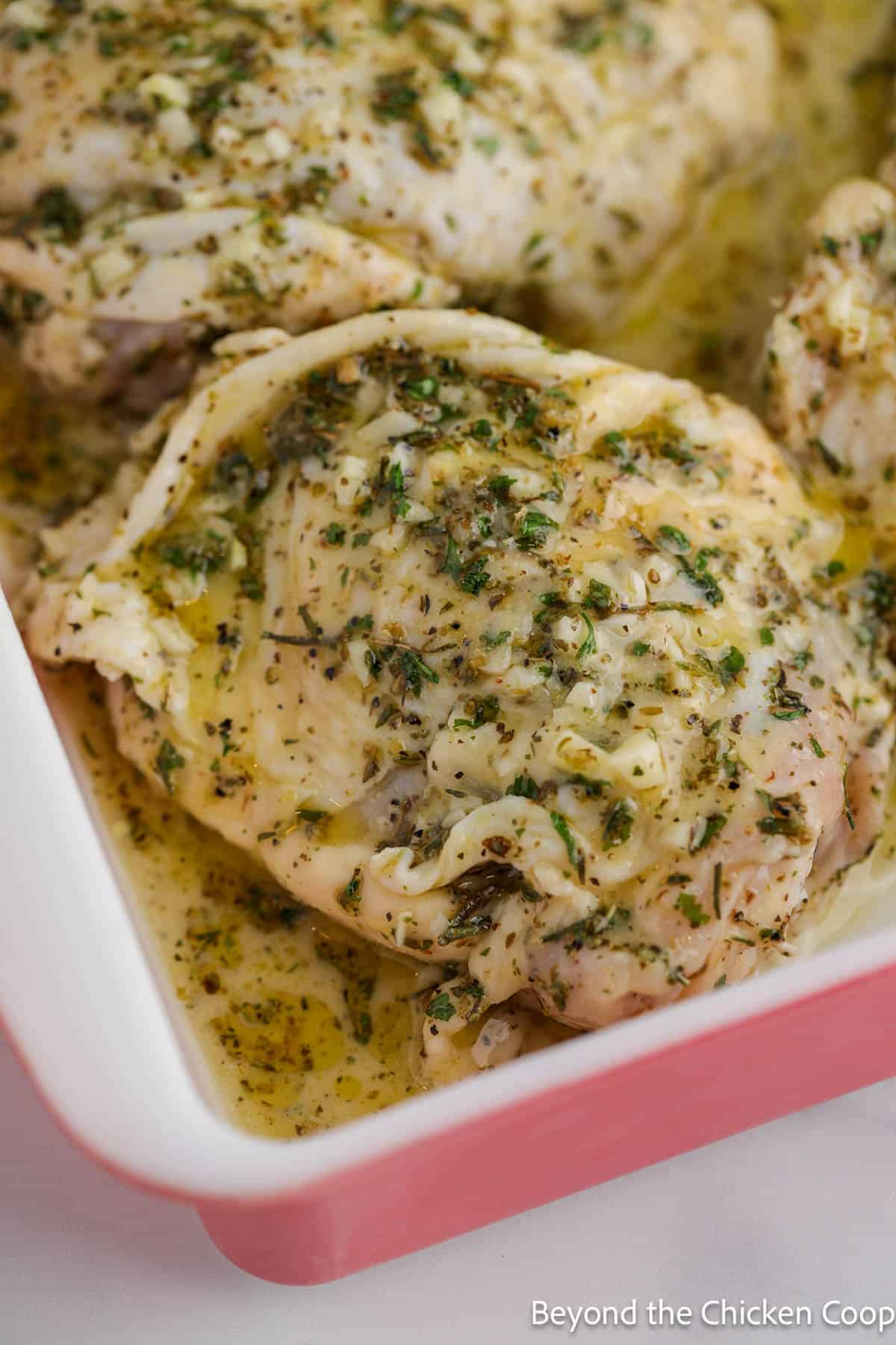 Chicken thighs covered with herbs in a baking dish. 
