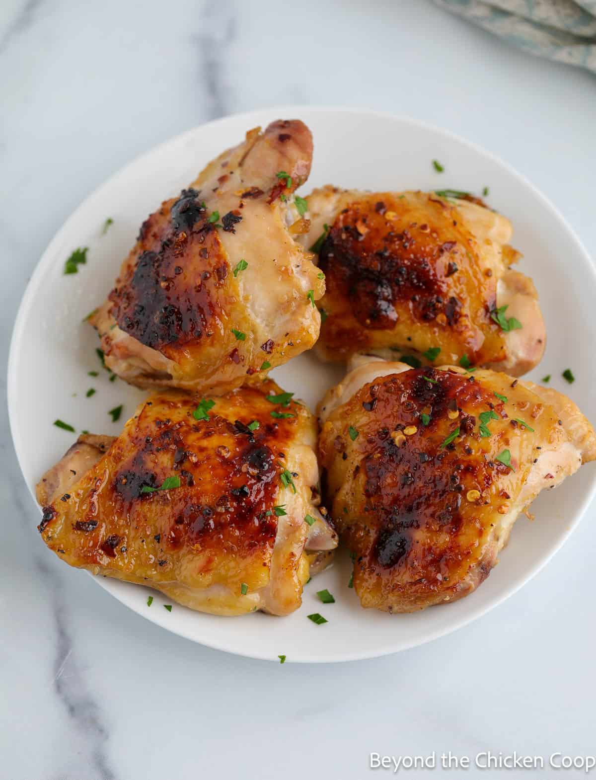 Four chicken thighs on a plate. 
