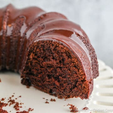 A chocolate bundt cake on a white cake stand.