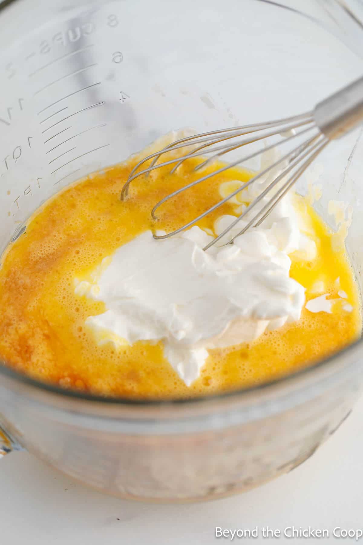 A mixing bowl with eggs and sour cream. 
