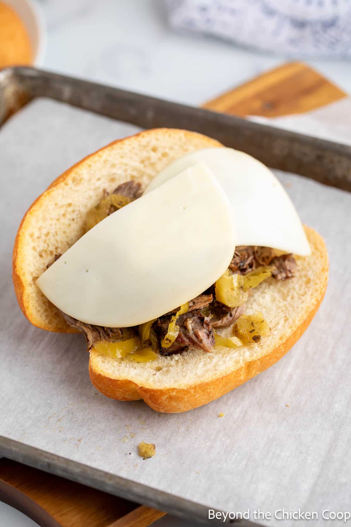 Sliced provolone cheese on shredded beef. 