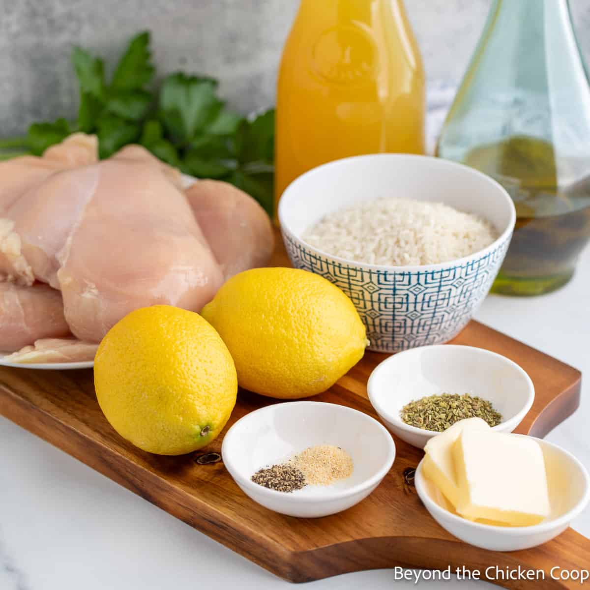 Uncooked chicken, whole lemons and seasoning on a wooden board. 