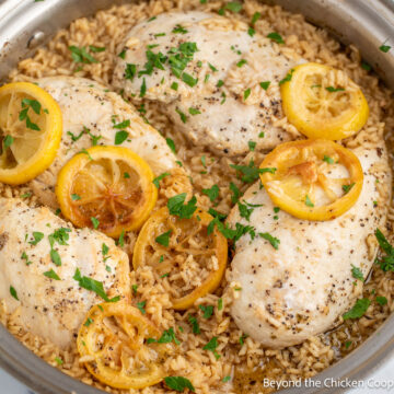 Chicken breast with lemon and rice in a skillet.