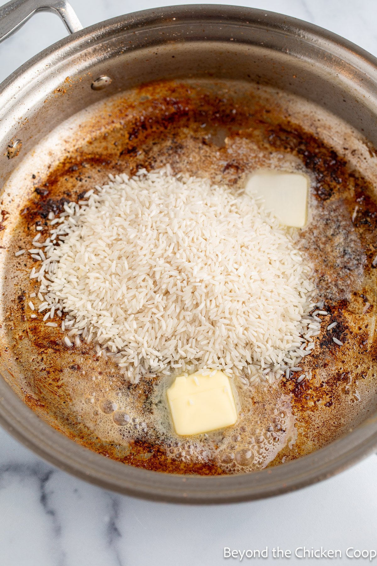 Pats of butter and rice in a skillet.