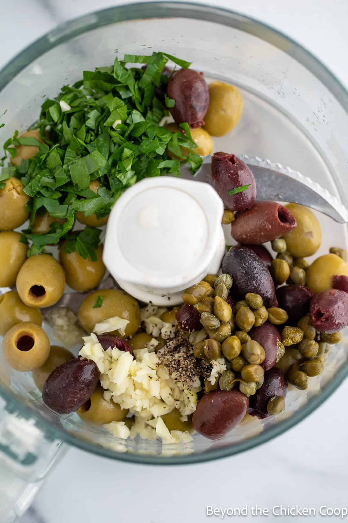 Green and black olives in a food processor. 