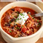 A bowl of chili topped with cheese and sour cream.