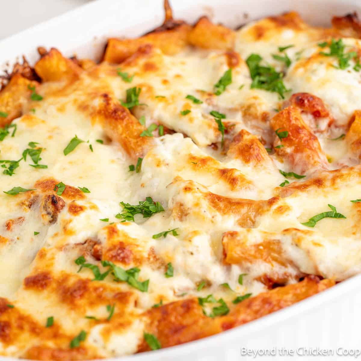 Baked rigatoni with sausage topped with cheese and parsley.