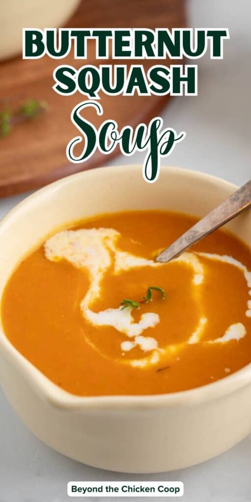 A bowl of squash and carrot soup drizzled with cream.