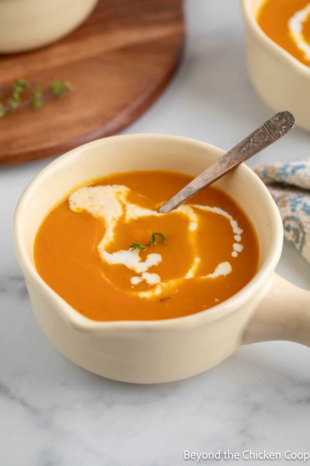 A bowl of butternut and carrot soup with a spoon in the bowl. 