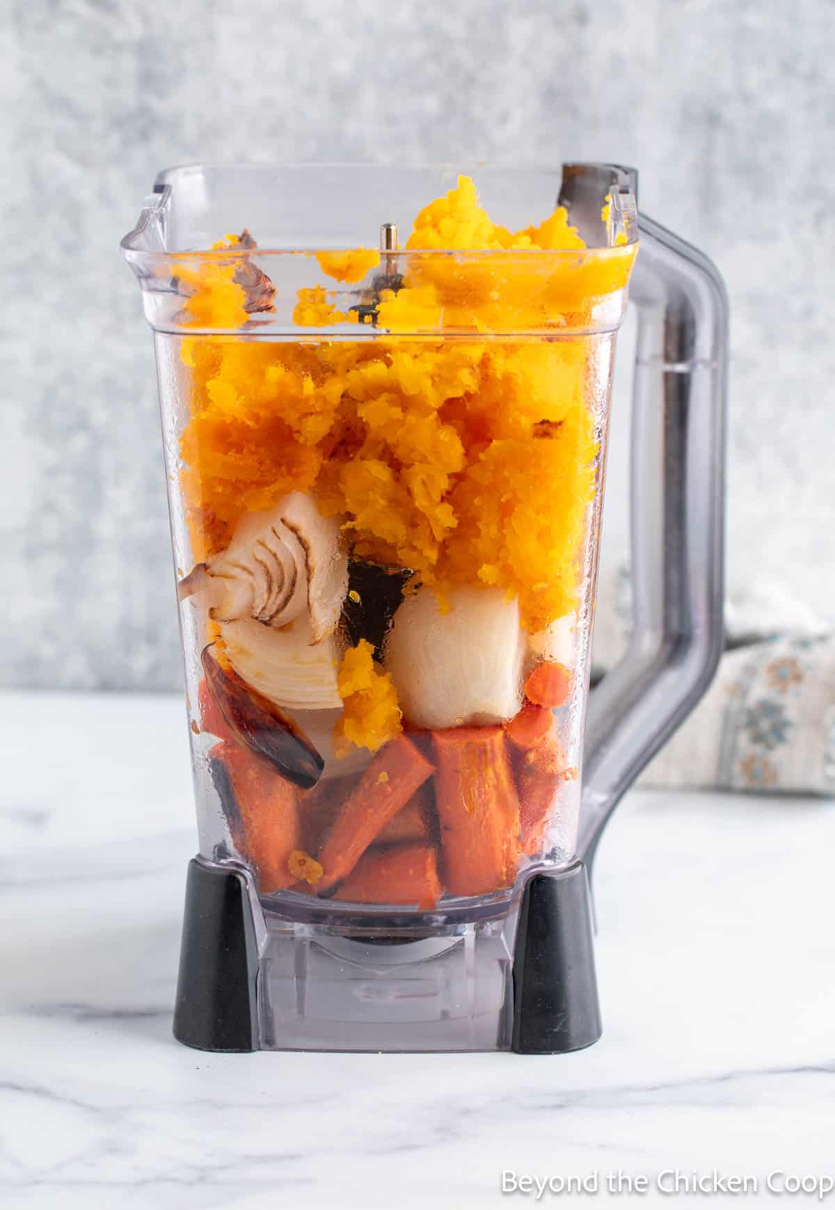 A blender filled with roasted vegetables. 