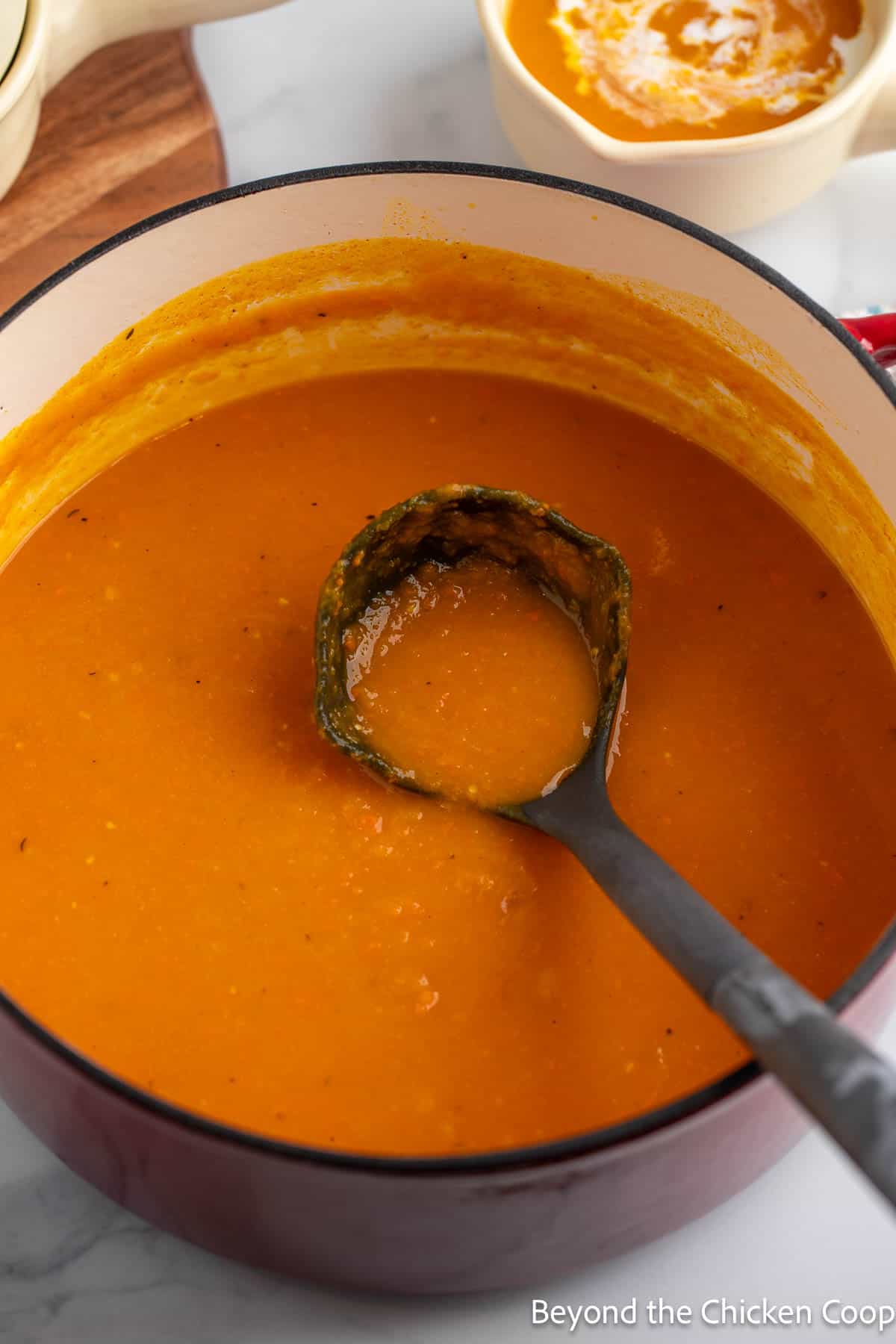 Roasted Butternut and Carrot Soup in a large pot with a soup ladle.