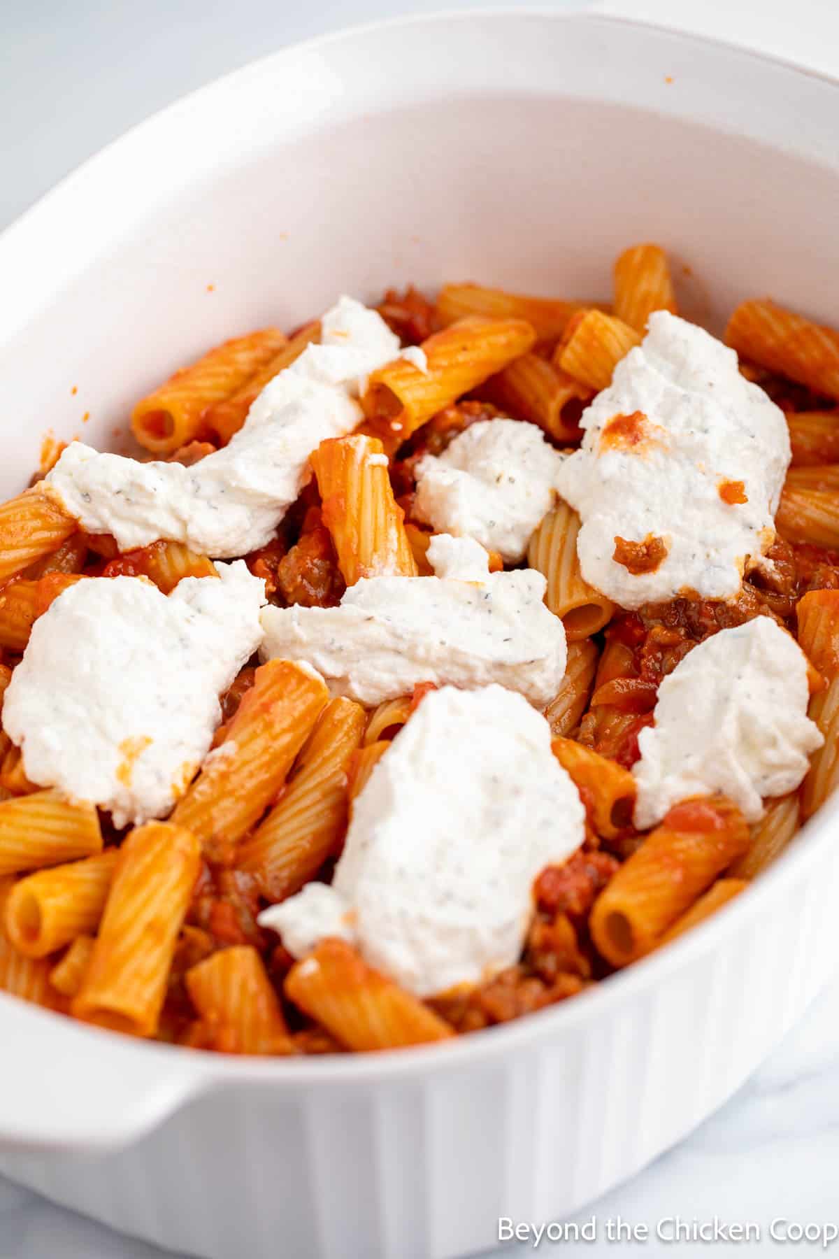 Layering a pasta casserole in a casserole dish.