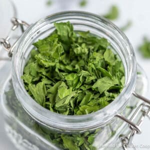 A glass crock filled with dried parsley.