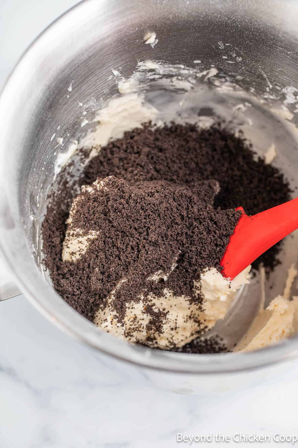Finely ground oreo cookies in a bowl of frosting. 