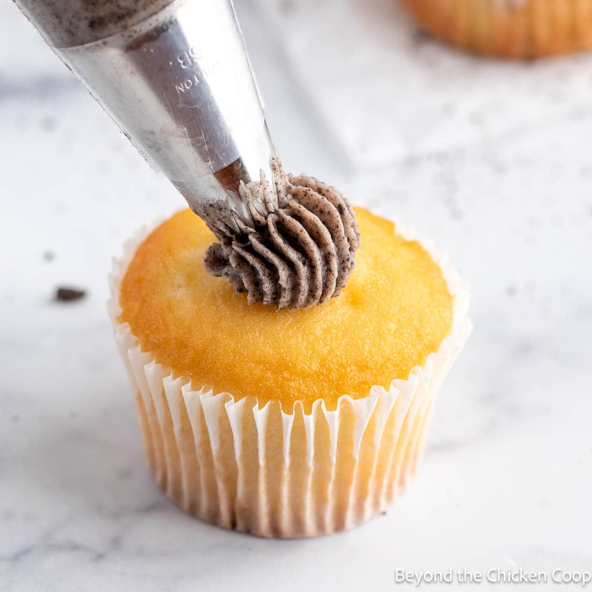 Piping Oreo Buttercream Frosting onto a cupcake. 