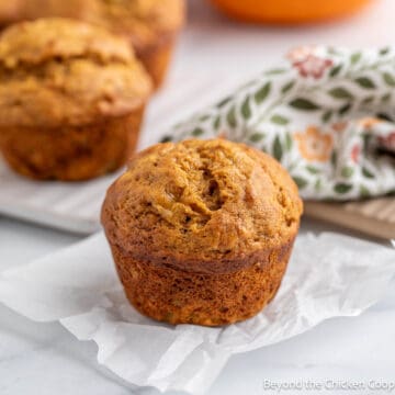 A pumpkin banana muffin on a piece of parchment paper.