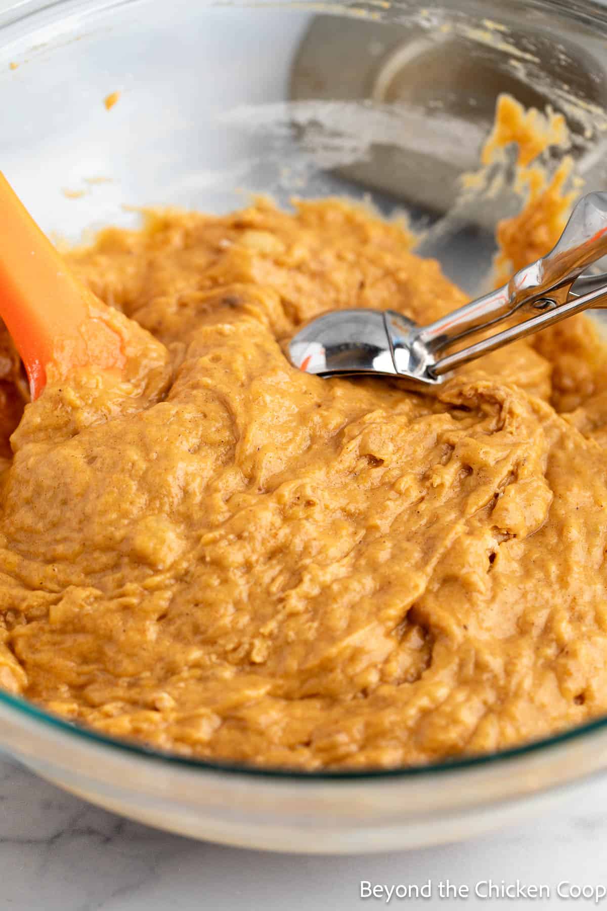 Scooping muffin batter with an ice cream scoop. 