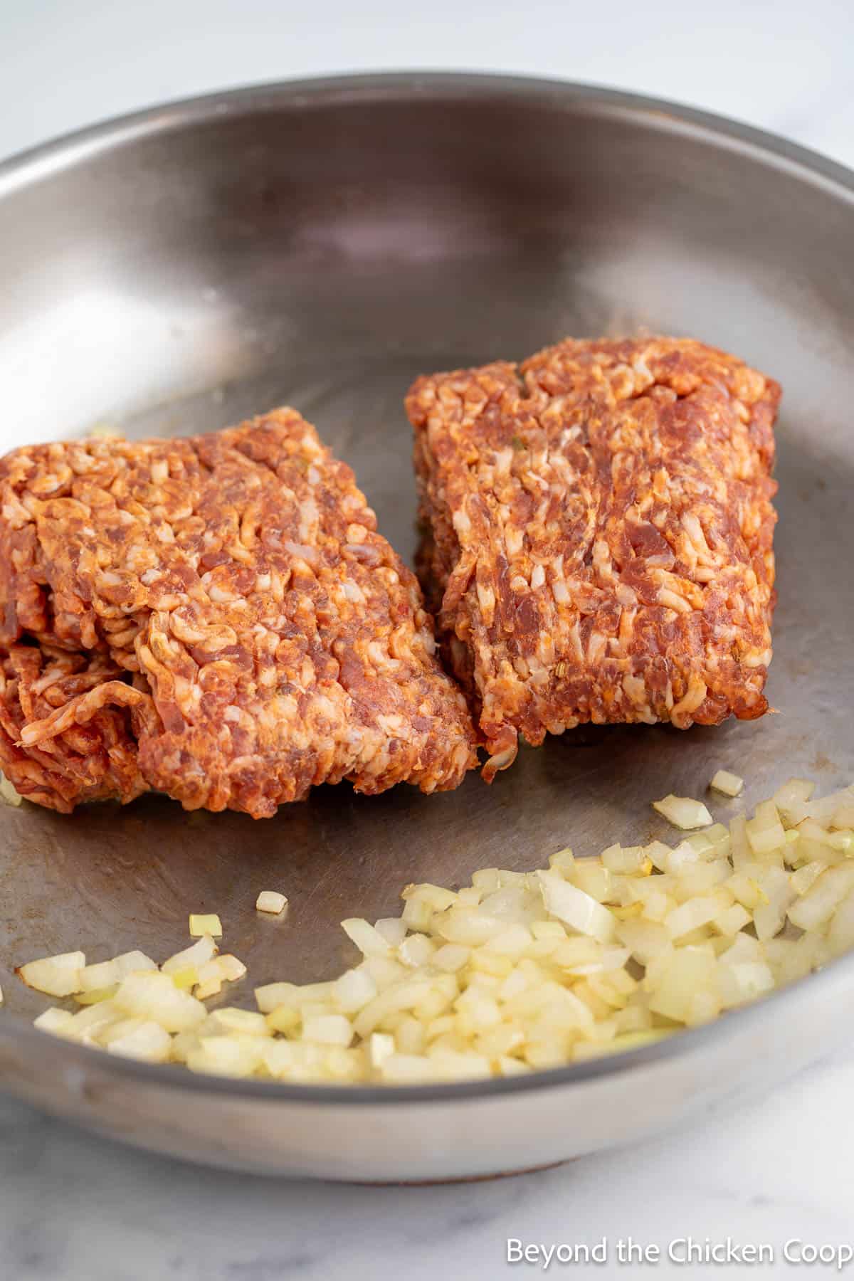 Italian sausage and sauteed onions in a pan. 