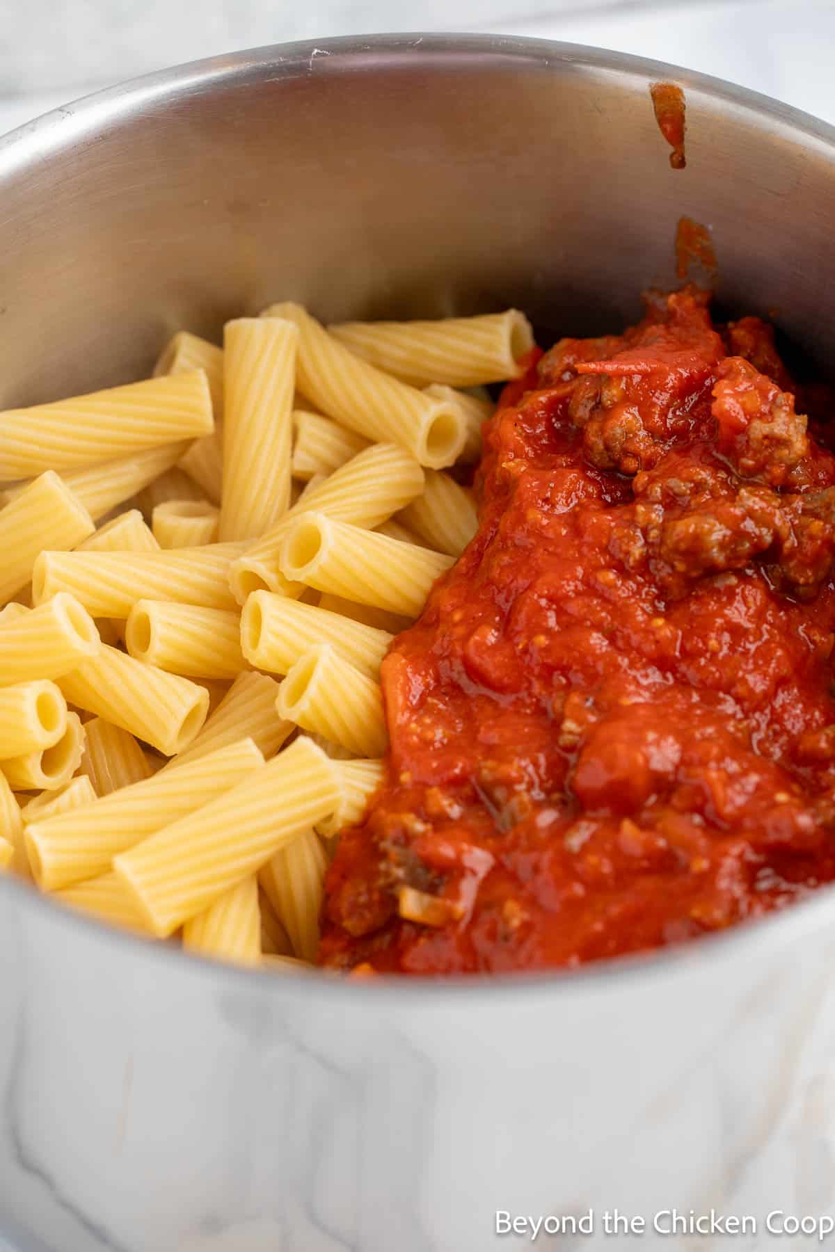 Cooked pasta with marinara sauce in a pot.