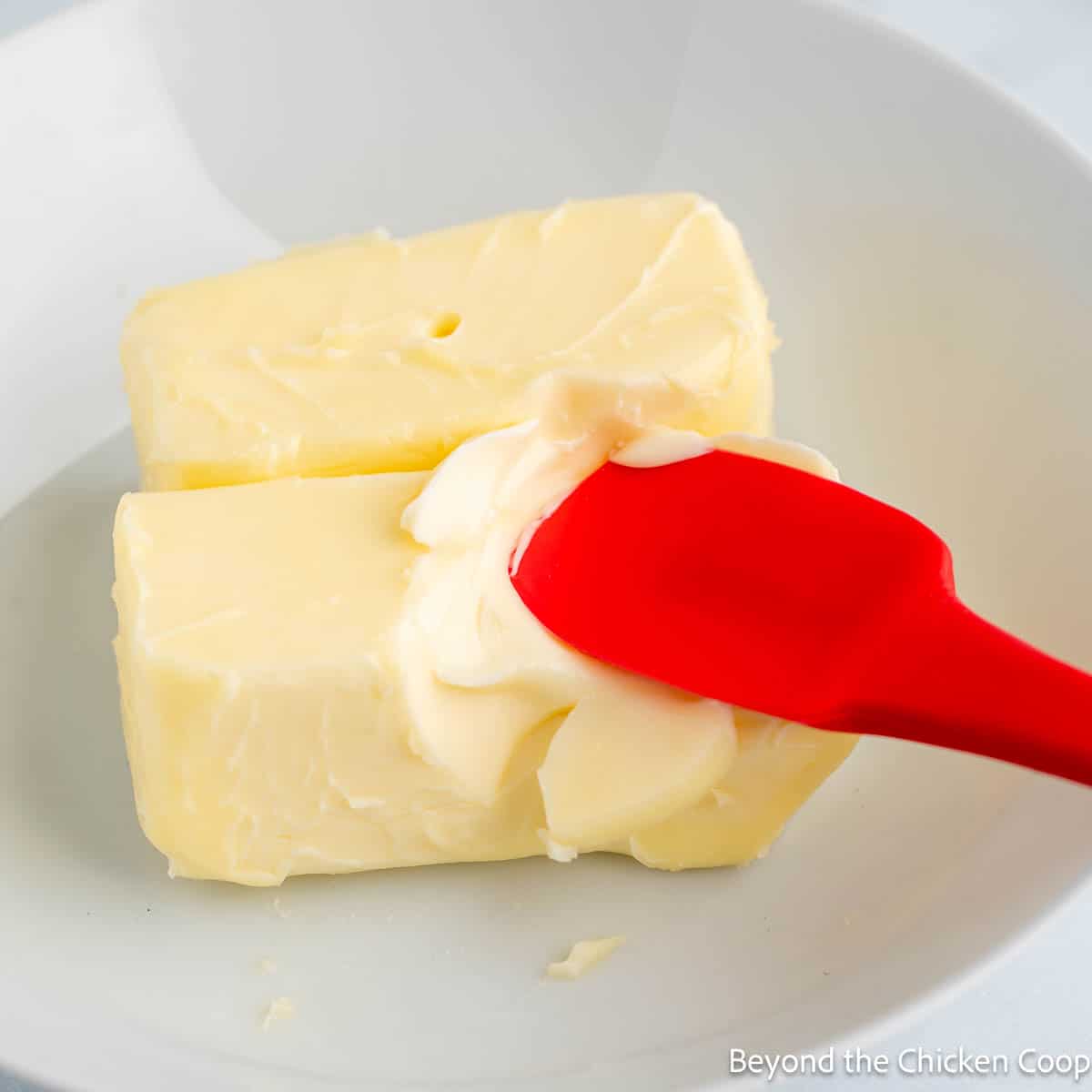 Softened butter being mashed with a spatula. 