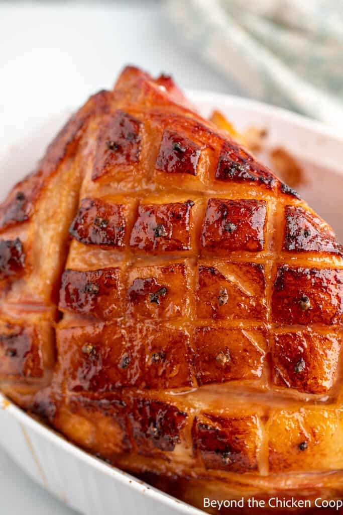 A baked ham with an orange glaze in a baking dish. 