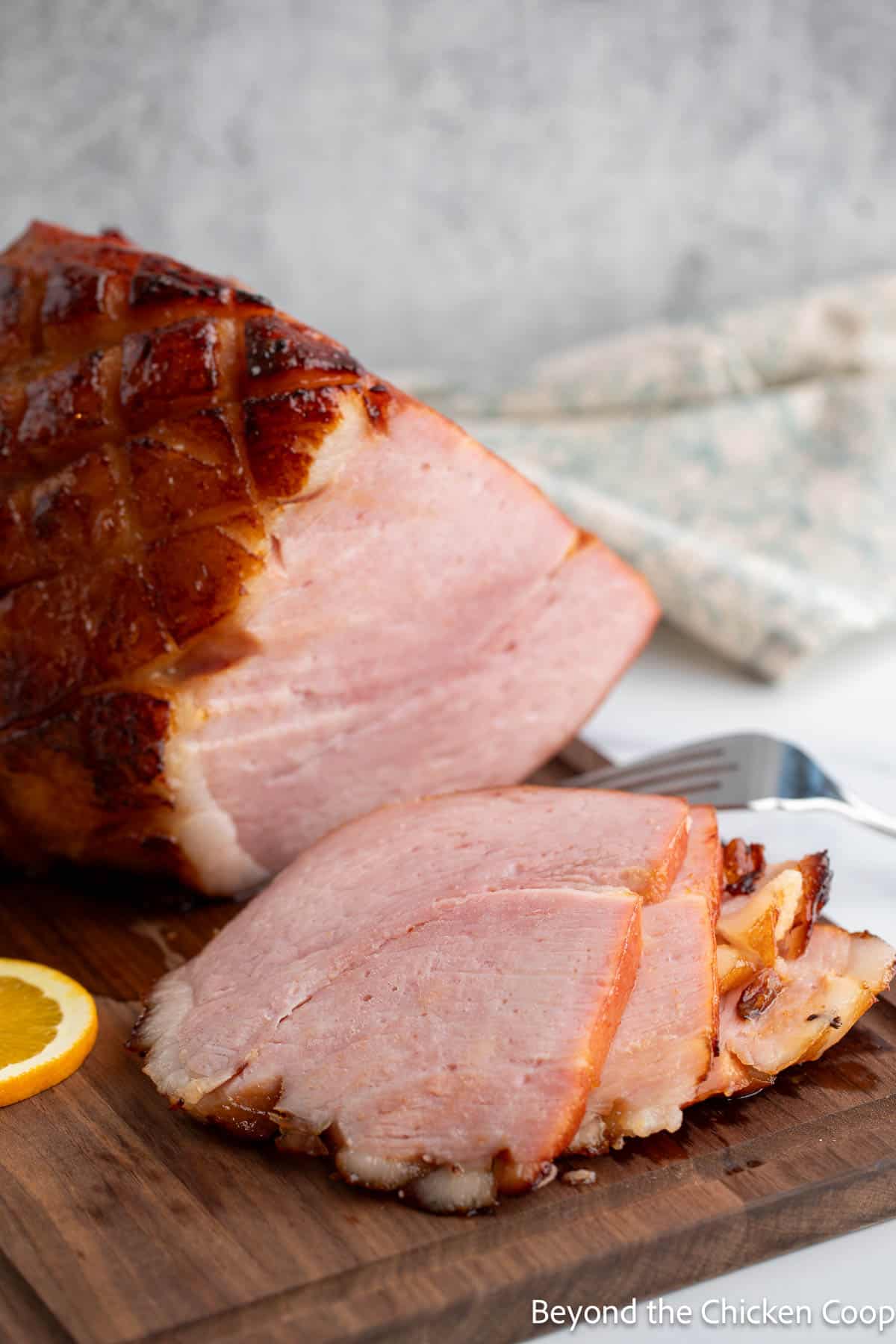 A slice ham topped with a citrus glaze on a cutting board. 