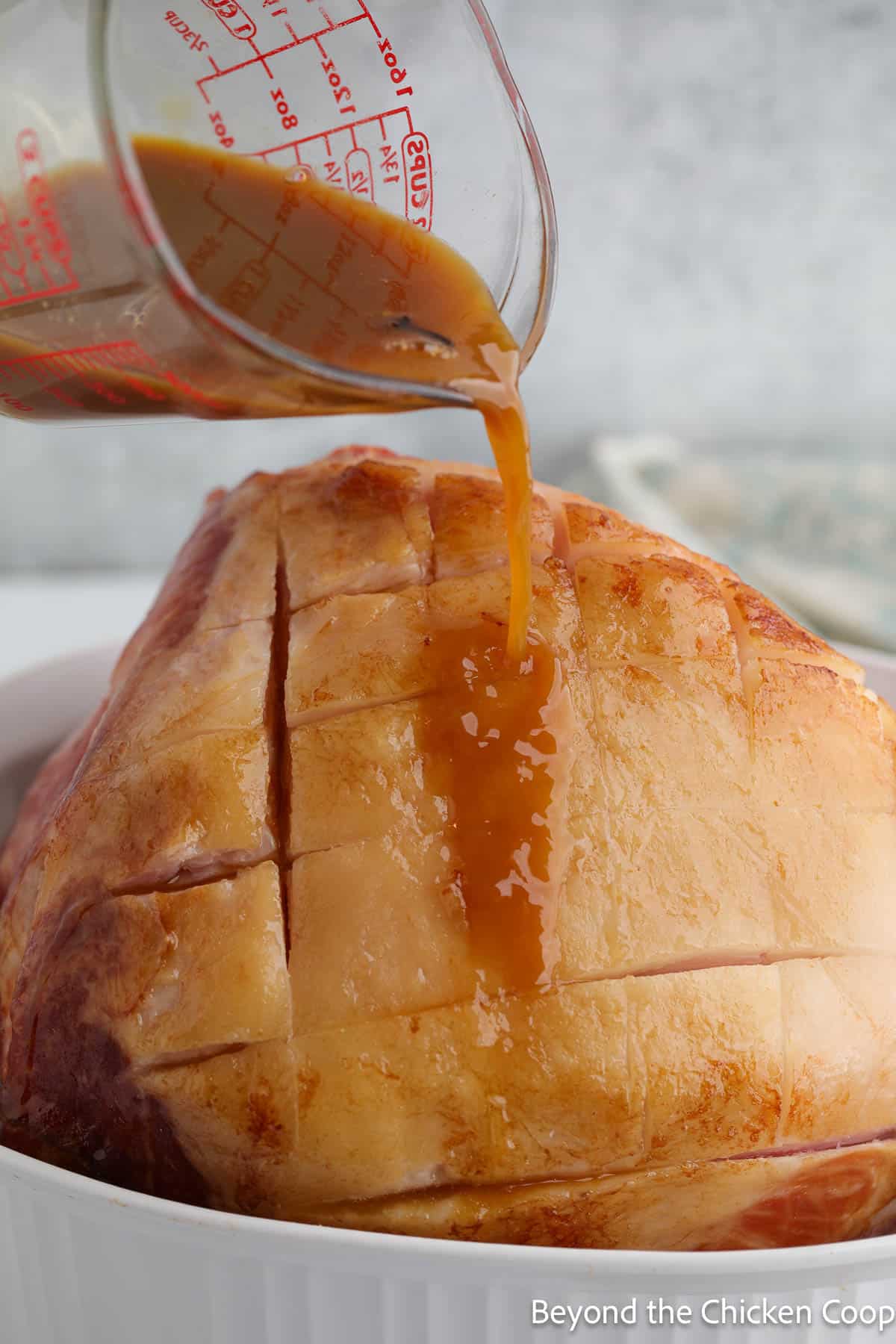 Pouring a glaze over a partially baked ham.