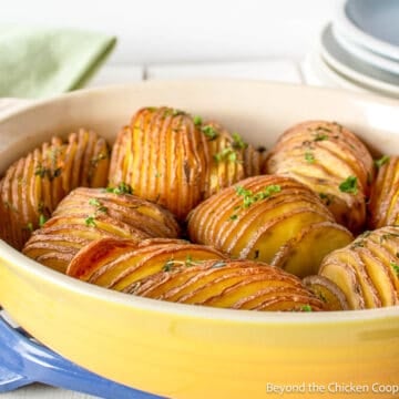 Thinly sliced mandoline potatoes in a yellow casserole dish.