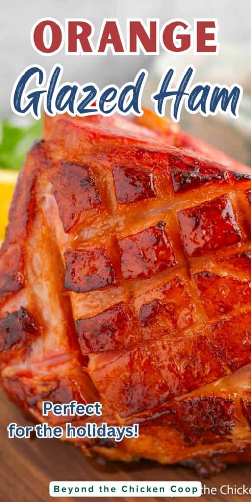 An orange glazed ham with score marks on the crust.
