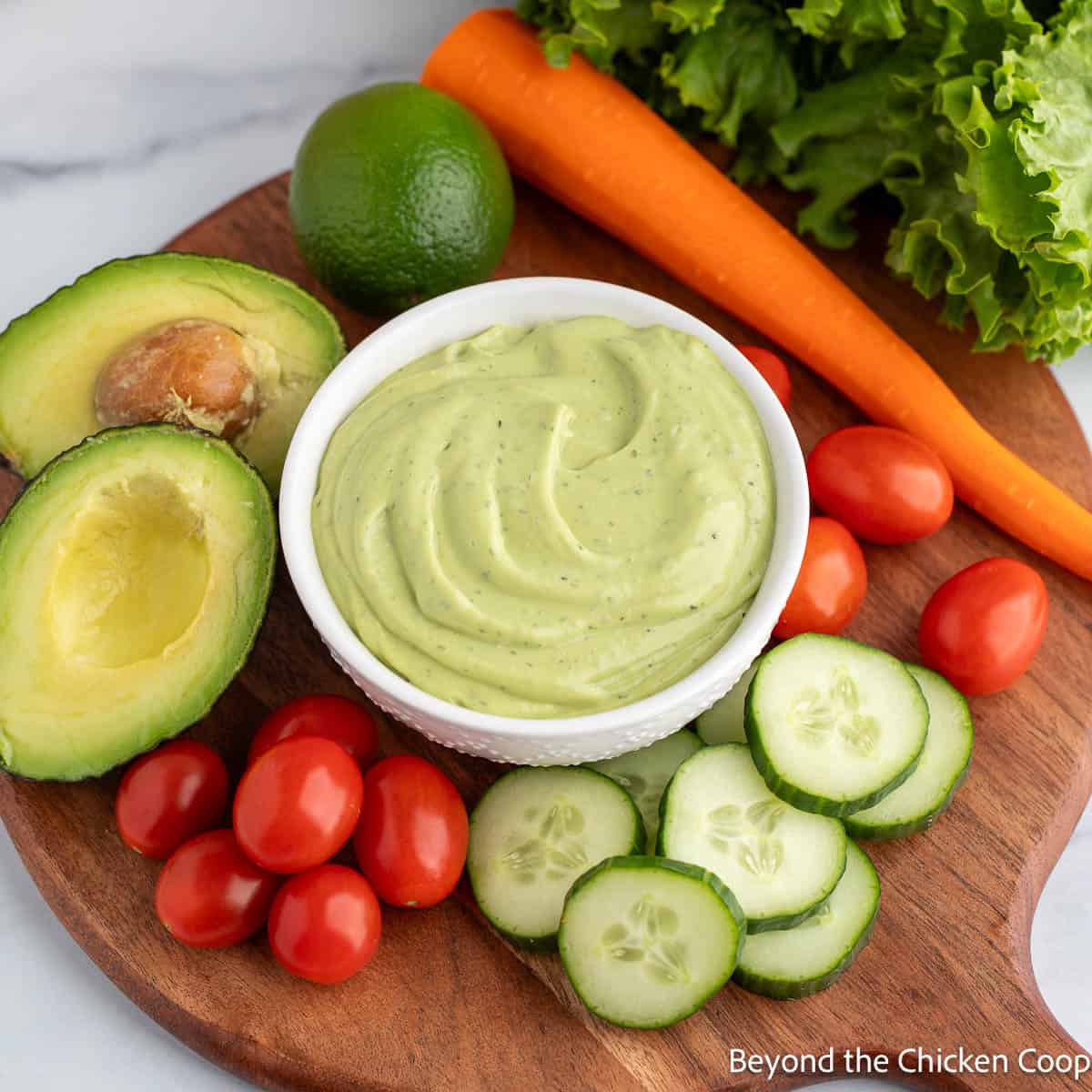 Avocado Ranch Lime Dressing in a bowl surrounded by fresh veggies. 