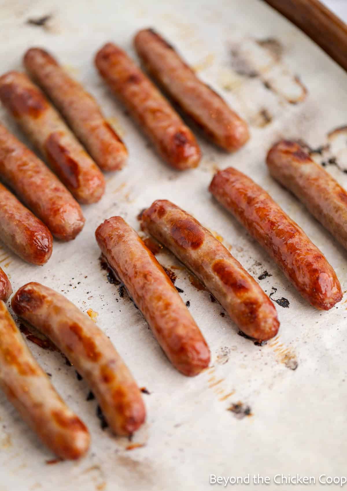 Cooked sausage links on a baking sheet. 