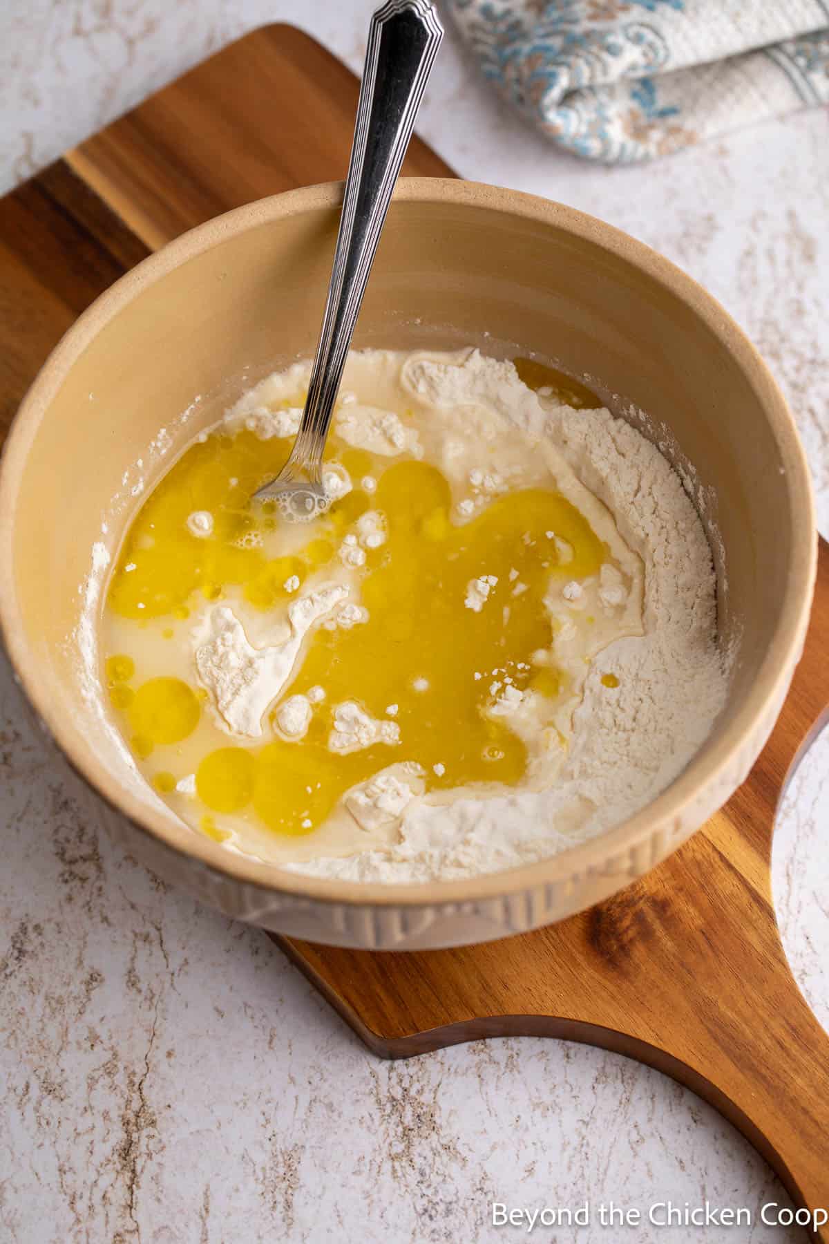 Flour, water and olive oil being mixed in a bowl. 