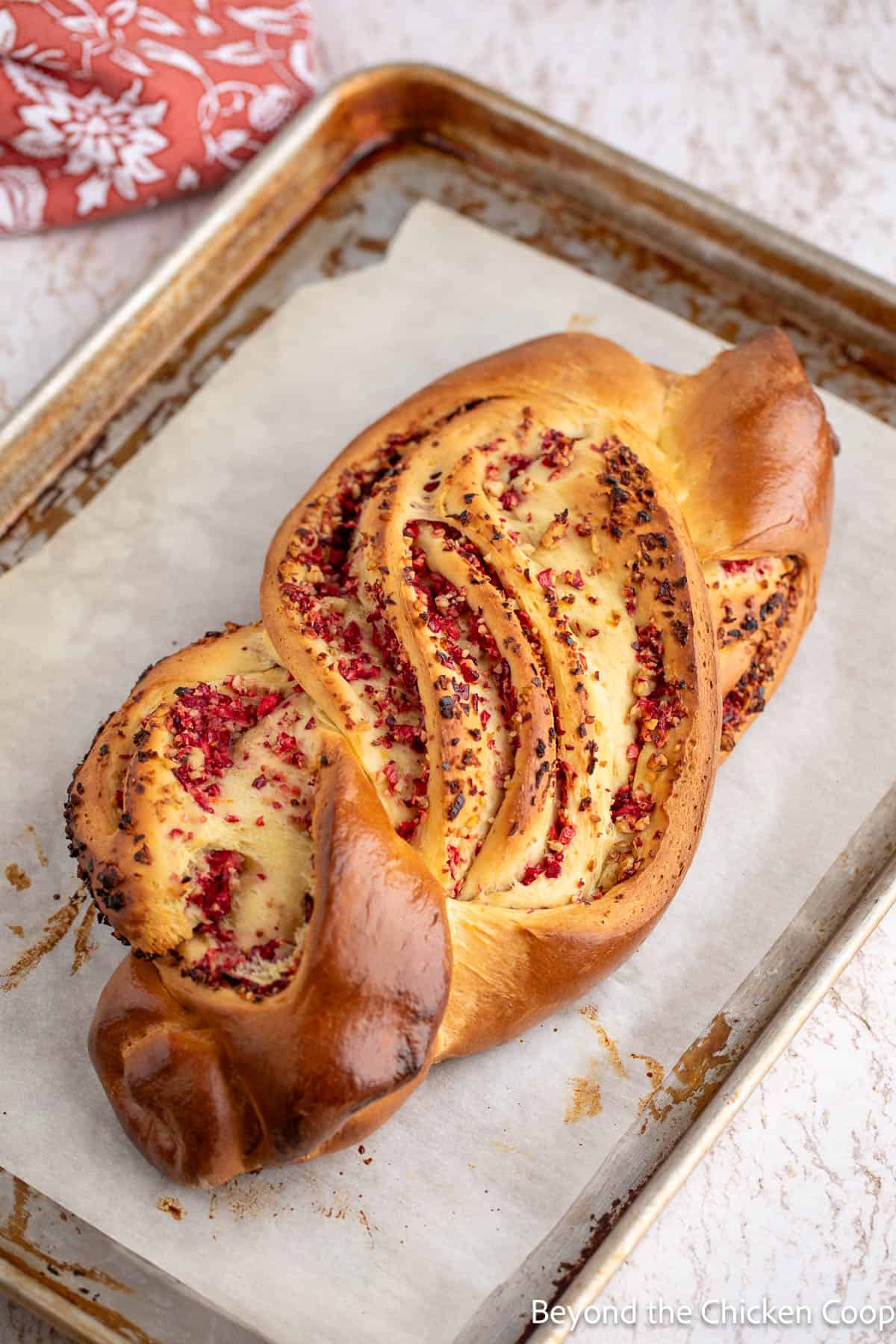 A baked loaf of cranberry walnut bread on a baking sheet. 