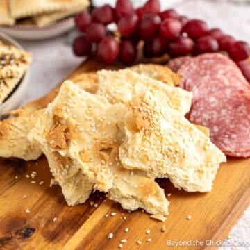 Rustic Flatbread Crackers on a wooden board with salami and grapes.