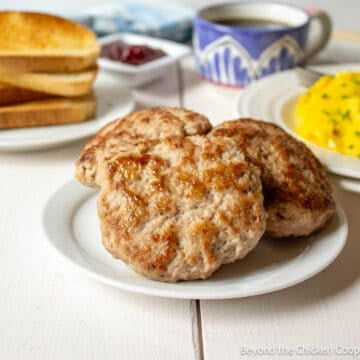 Three homemade breakfast sausages on a white plate.