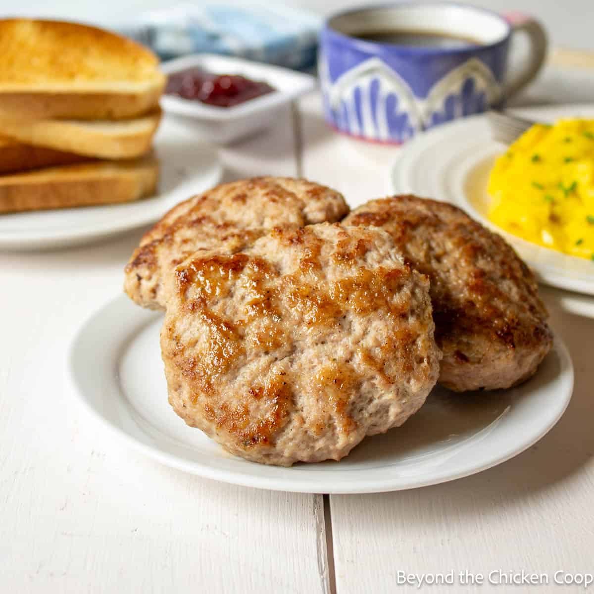 Three homemade breakfast sausages on a white plate. 