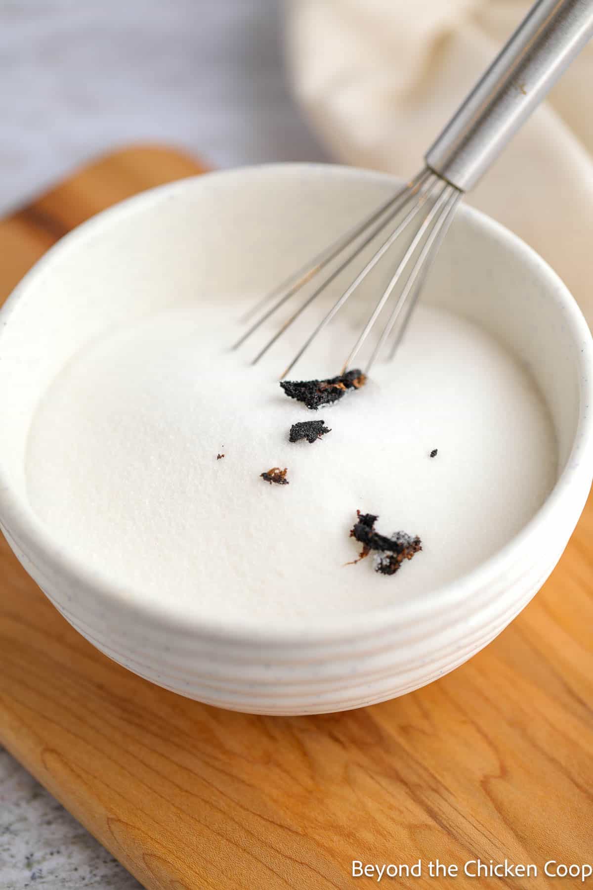 Vanilla in a bowl of sugar with a whisk. 